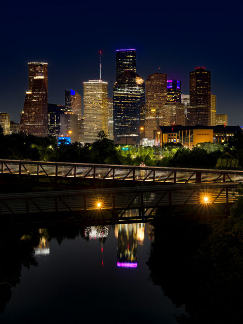 Downtown Houston Texas evening skyline with pedestrian bridges crossing over the bayou in the foreground. 