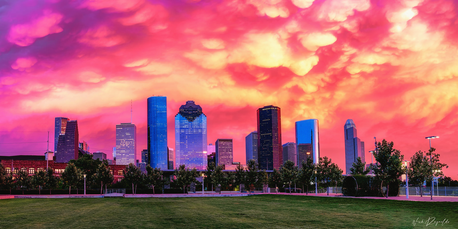 Pink, purple, and orange sunset with clouds overlooking the downtown Houston skyline. 
